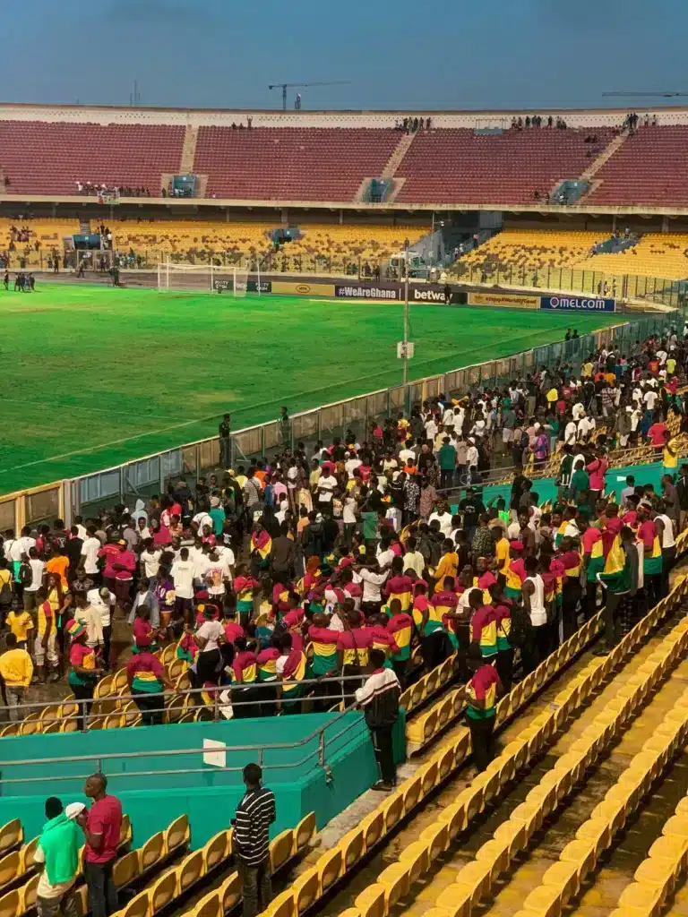 Scene at Accra Sports Stadium in Ghana with fans wearing vibrant flag colors
